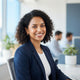 A smiling, diverse woman in a professional office setting, representing a satisfied customer.